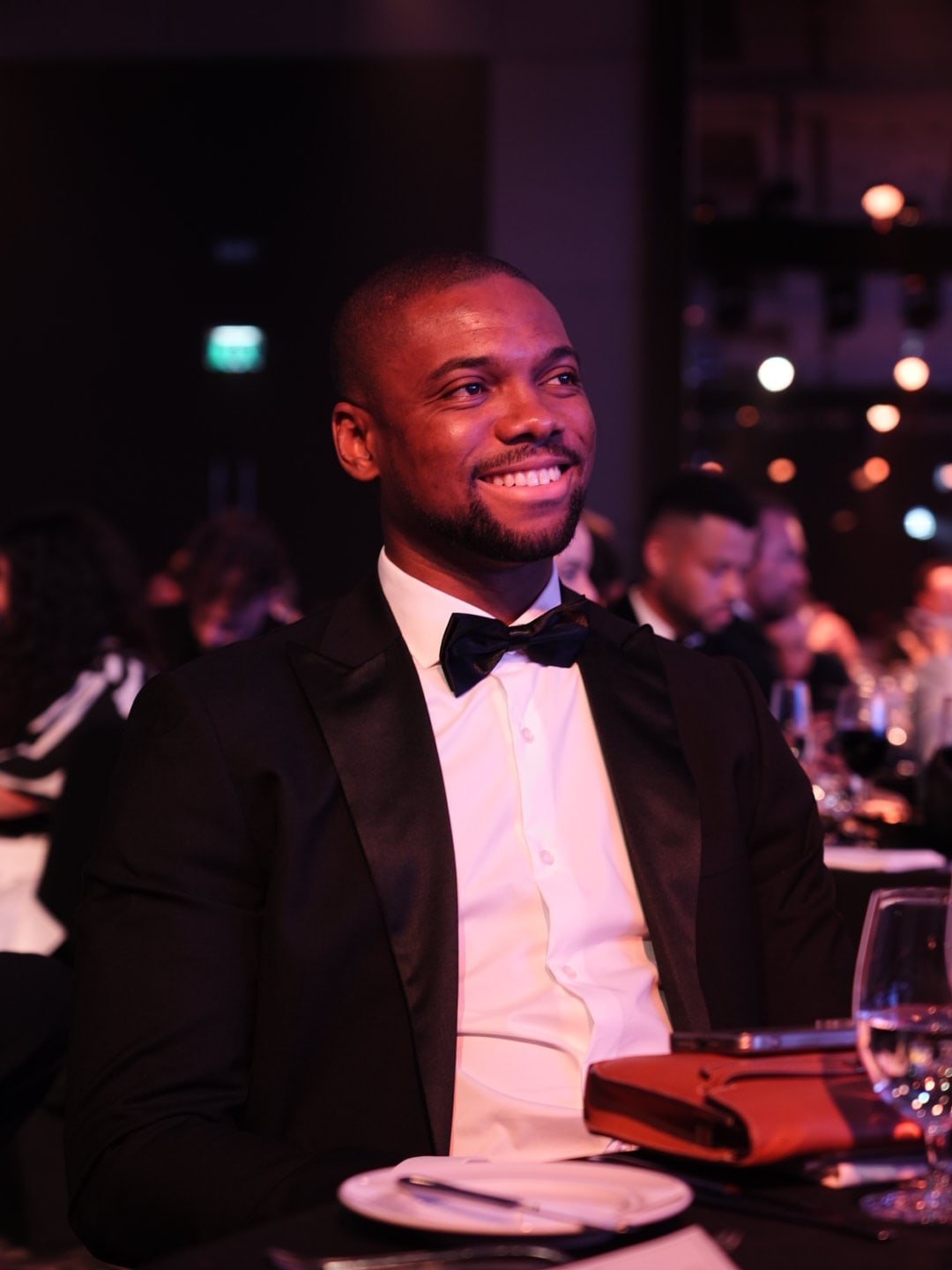 Side-profile portrait of Tonye Anyanwu in a black tuxedo